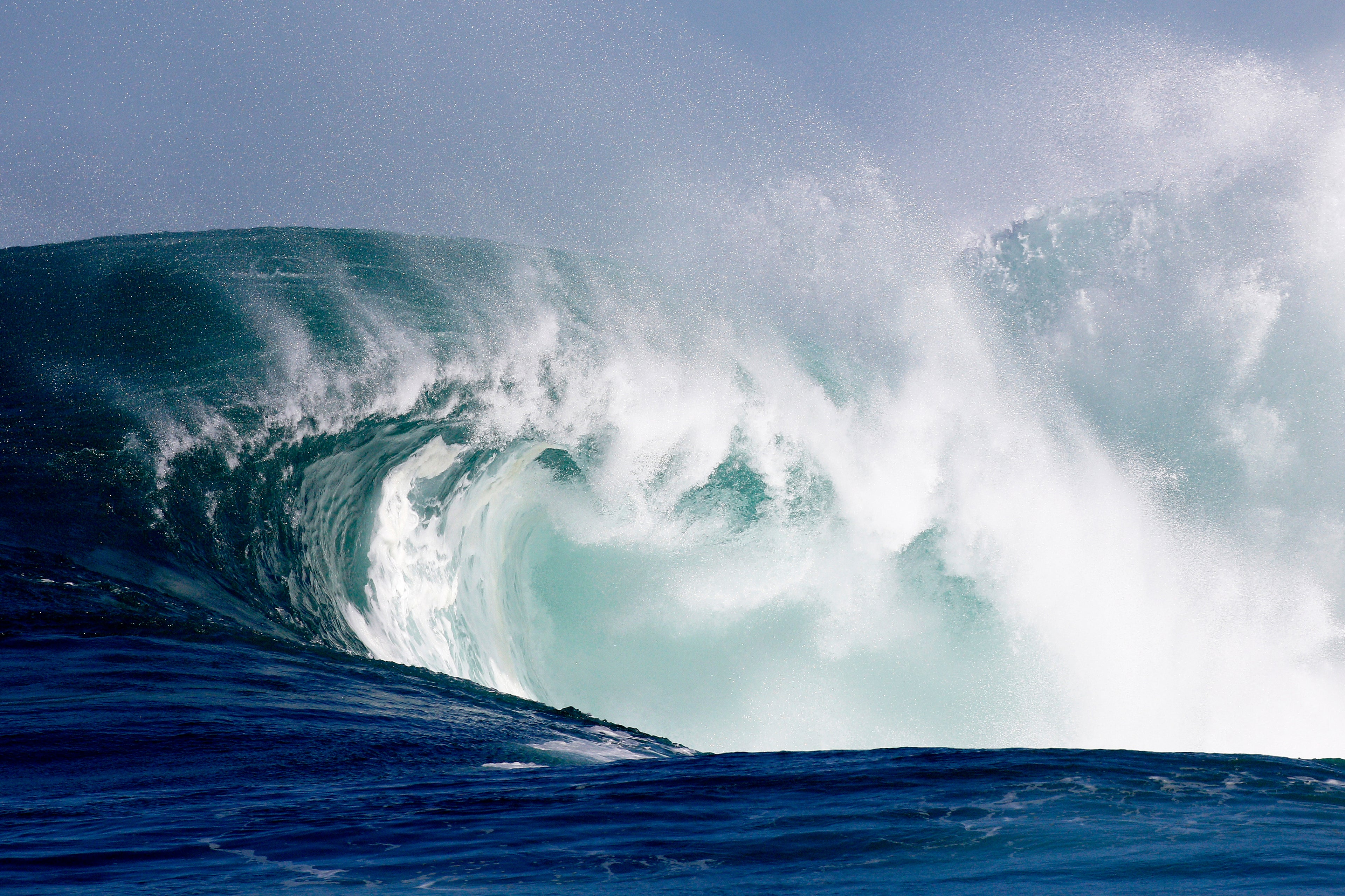 Powerful breaking wave with white foam curling over itself in the ocean.