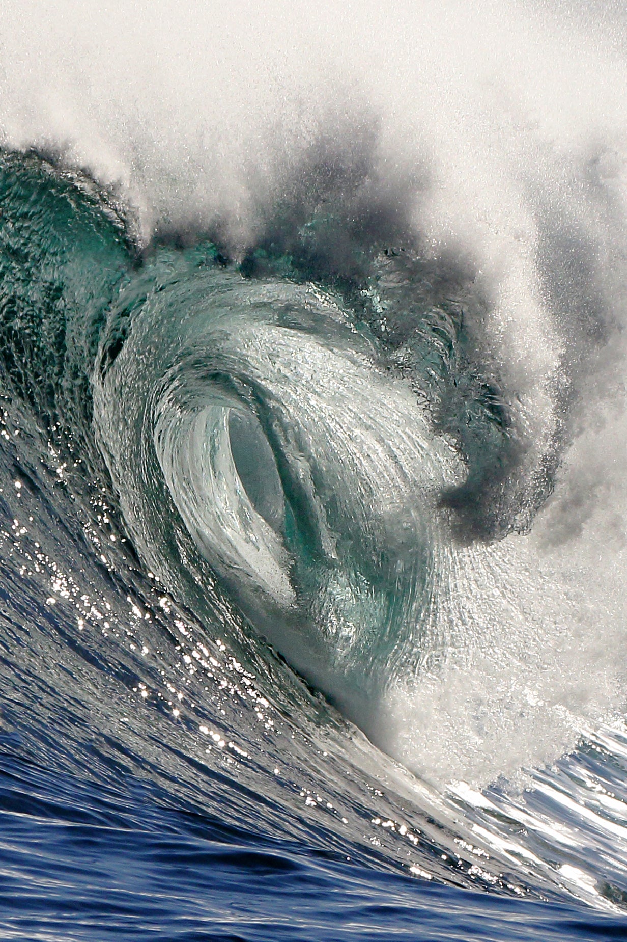 Close-up of a curling wave with water droplets glistening in the sunlight.